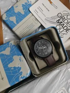 A chronograph watch in its presentation tin, photographed by the customer who received it