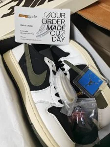 An olive and white low-top sneaker with its accessories still bagged