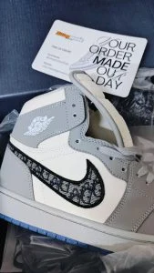 A grey and cream monogrammed high-top sneaker on delivery