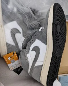 A grey suede and white high-top sneaker held up by the customer