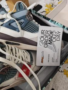 A pair of teal and cream high-tops in an opened delivery box