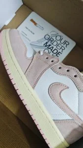 A pale pink and white low-top sneaker resting on its delivery box