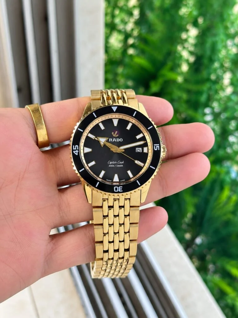 Gold-tone 42mm automatic dive watch with a black dial and black ceramic bezel
