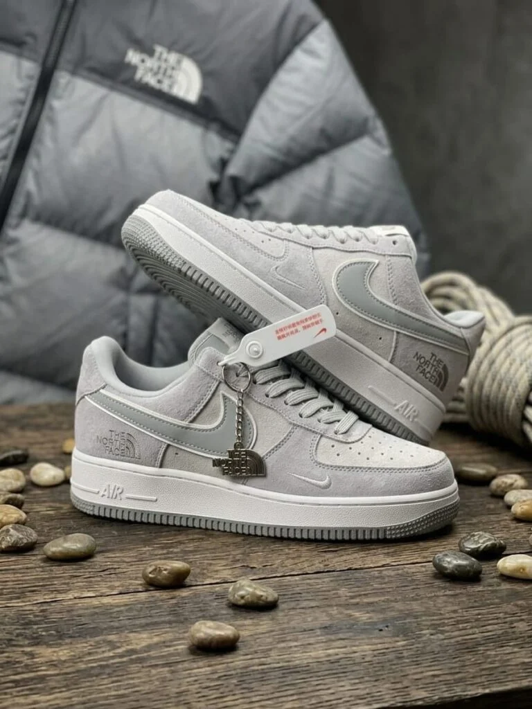 Grey and white low-top suede sneaker with a metal charm on the laces