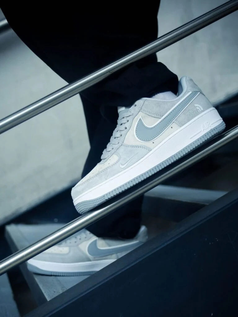 Grey and white low-top suede sneaker with a metal charm on the laces
