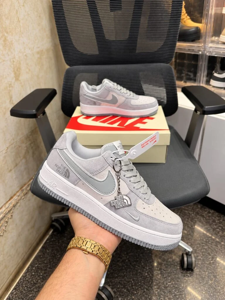 Grey and white low-top suede sneaker with a metal charm on the laces