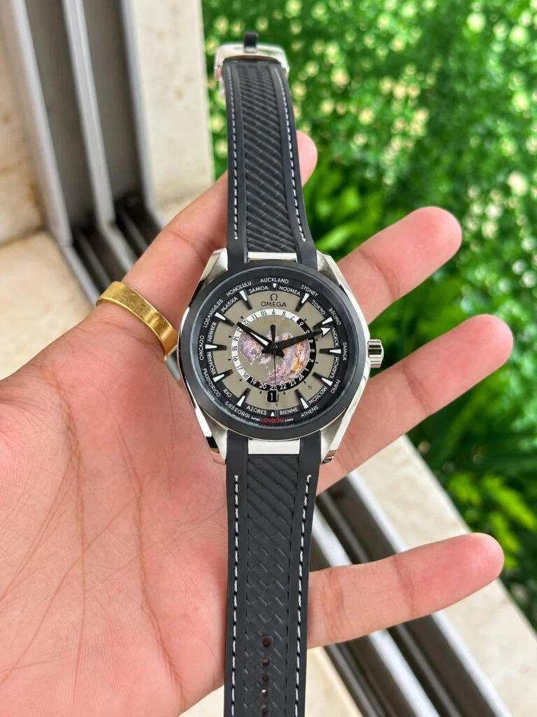 World map automatic watch with a grey dial, held in the hand